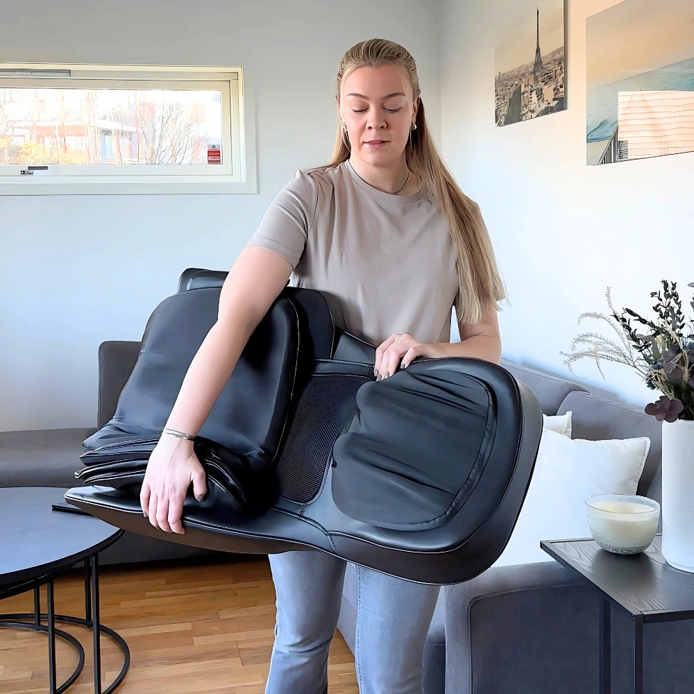 Kvinne bærer sammenleggbar Zenova massasjestol for enkel transport. Lett og praktisk design for bruk hvor som helst.
